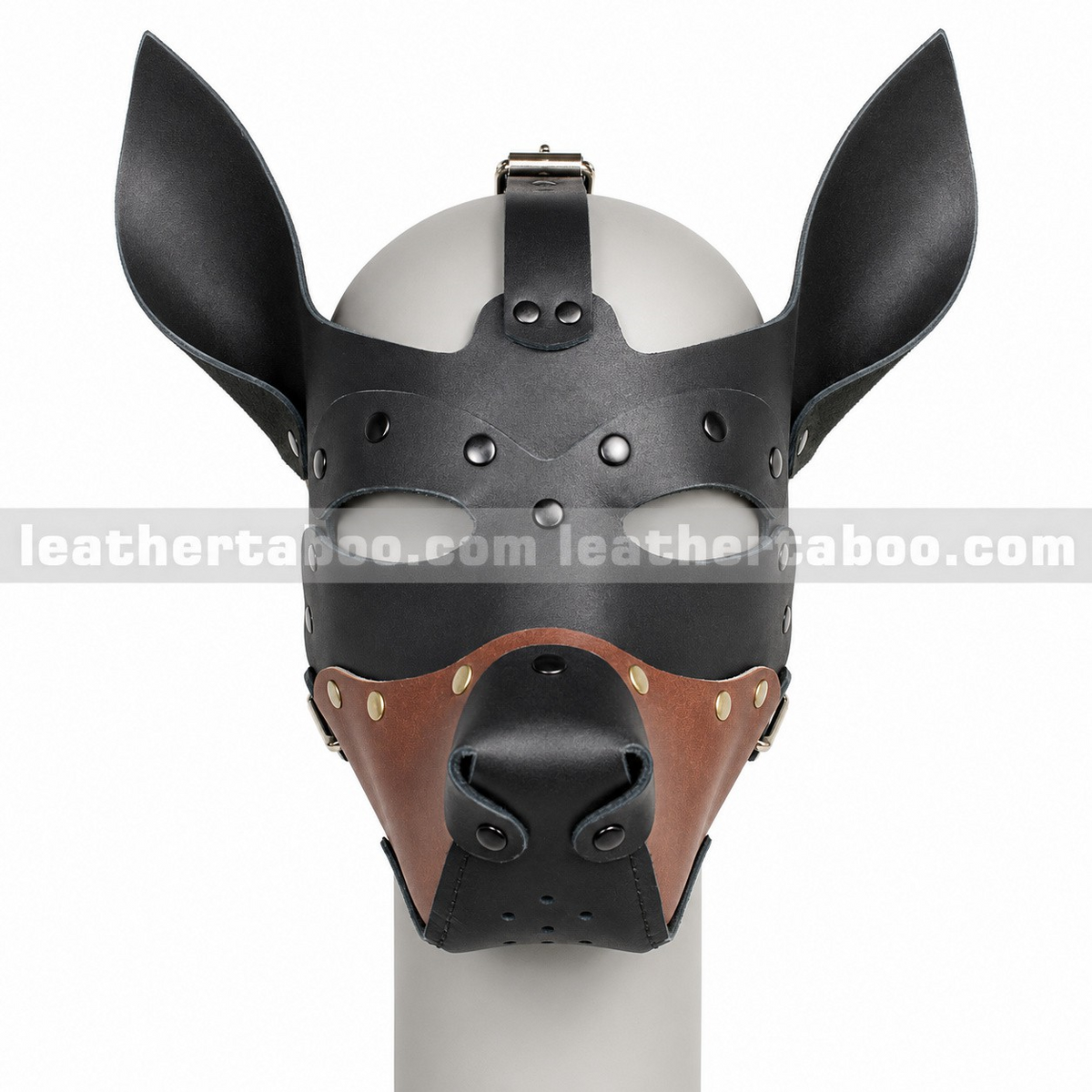 Front view of black and brown leather dog mask showing pointed ears, eye openings, sculpted black nose and riveted muzzle on a white mannequin.