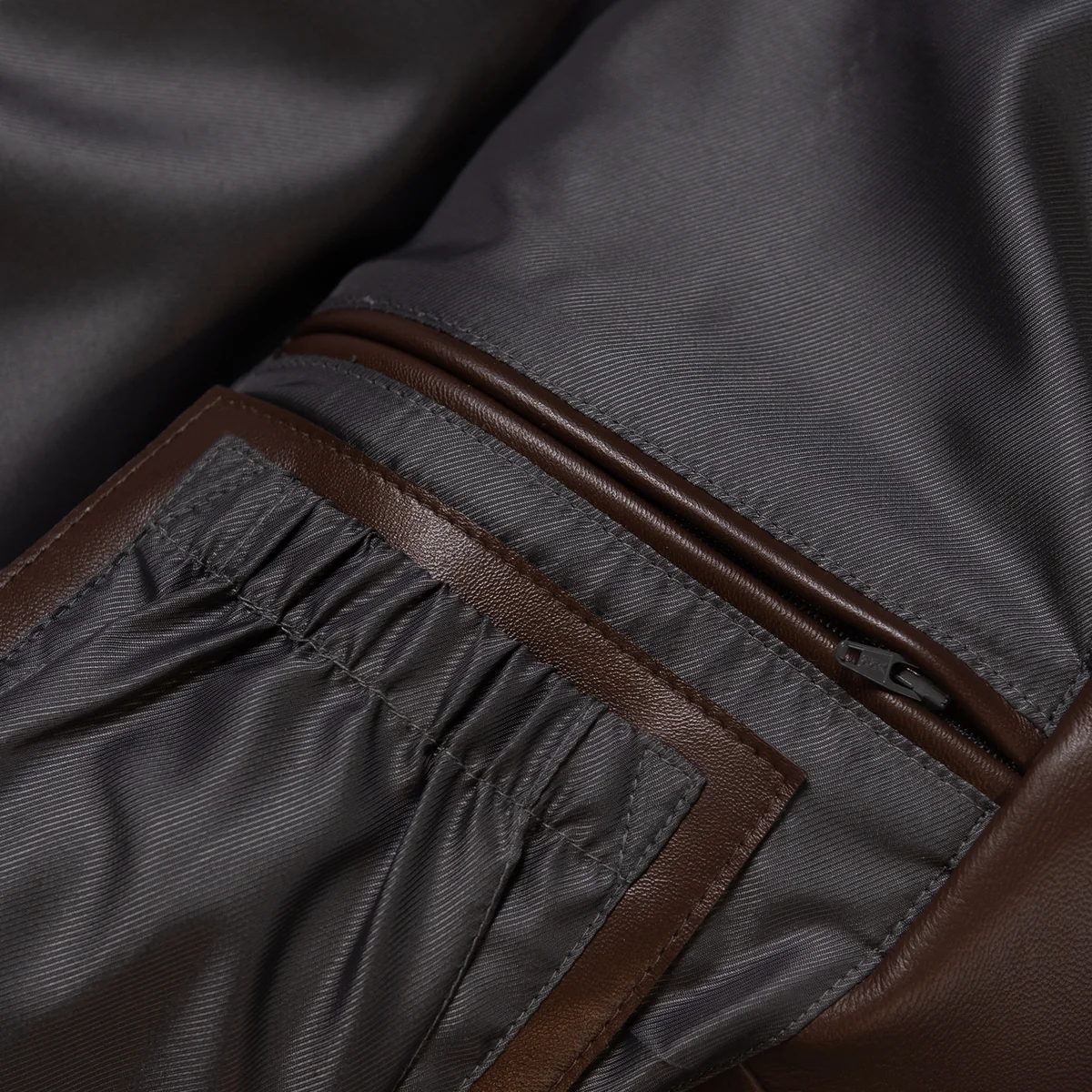 Interior detail of the racing sport jacket showing dark fabric lining, leather pocket trim, a zipped pocket and gathered pocket section.