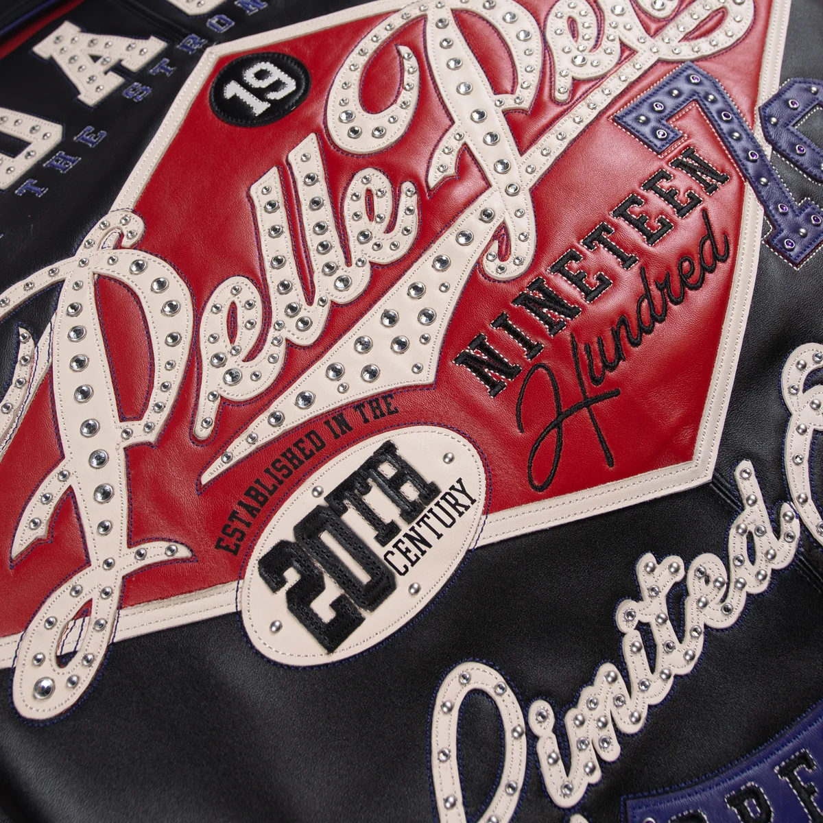 Close view of the jacket's red back patch with cream studded Pelle Pelle lettering, purple accents and embroidered decorative text.