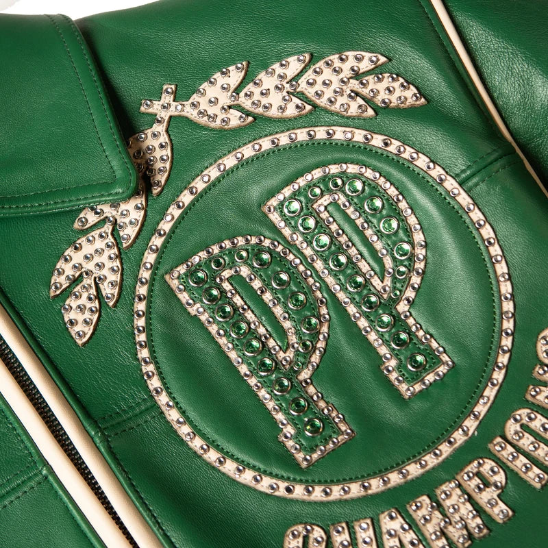 Close-up of Pelle Pelle Champions Jacket chest emblem showing ivory leather appliqué, green rhinestones, metal studs and detailed stitching.