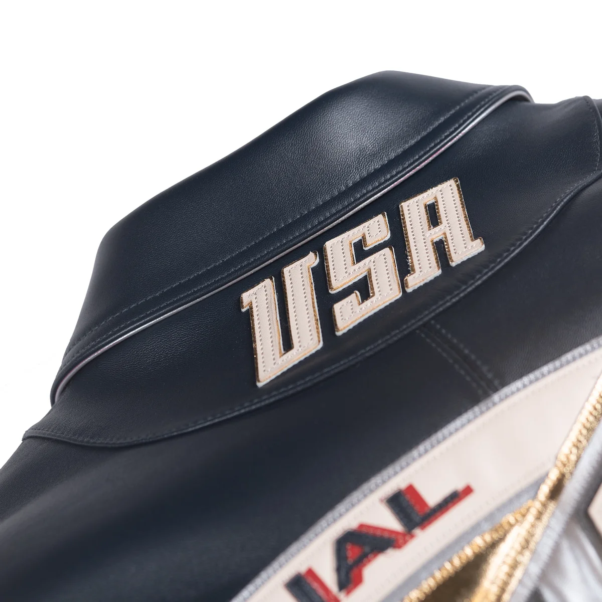 Close view of the black sport jacket's rear collar with stitched cream USA lettering, contrasting edging and smooth leather panels.